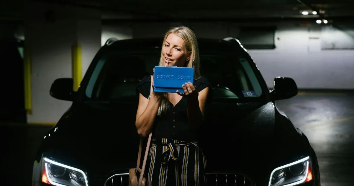 A Happy Woman Standing In Front Of Her Parked Car