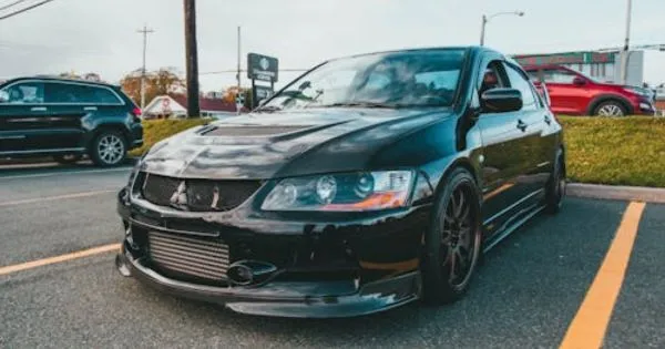 A Black Car Parked In An Urban Parking Lot With Some Other Vehicles