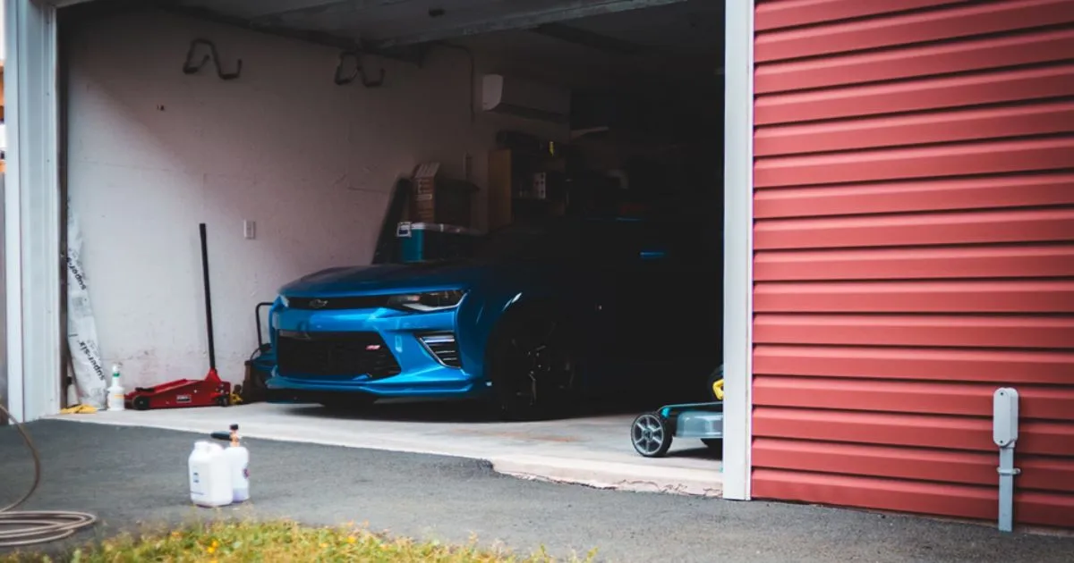 A Blue Car Parked In A Messy Garage
