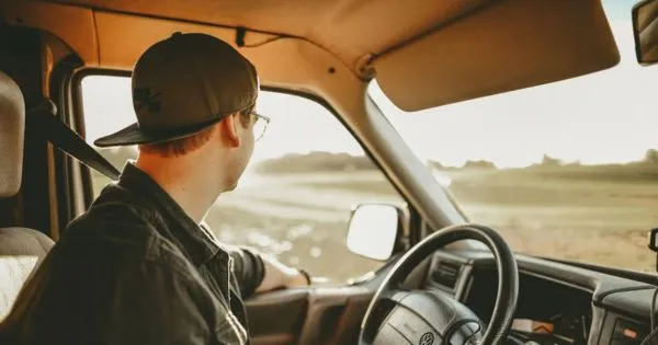 A Driver With His Hand Out Of The Window Of His Vehicle Looking Outside