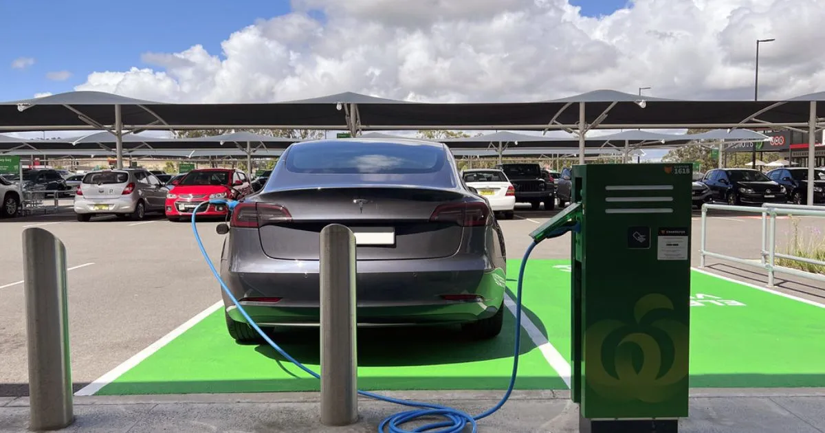 A Grey Electric Vehicle Is On Charging While The Owner Is Shopping In The Mall Conveniently A Grey Electric Vehicle Is On Charging While The Owner Is Shopping In The Mall Conveniently