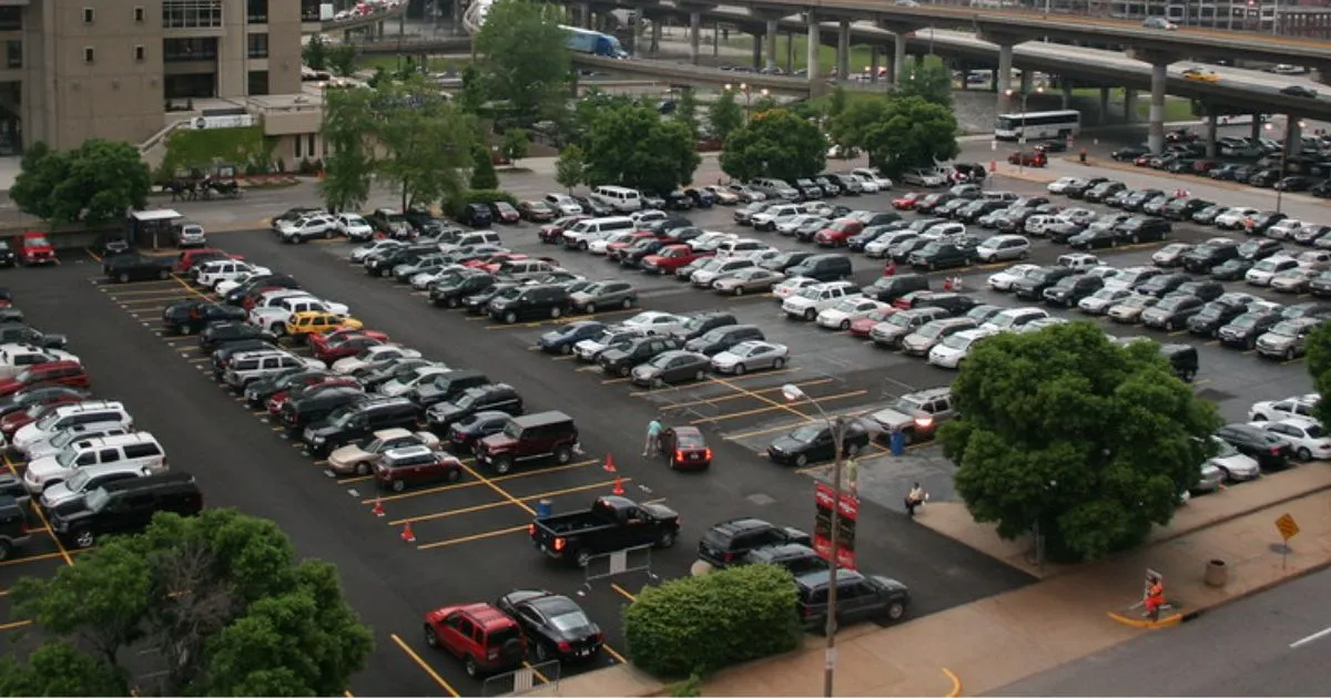 A Huge Parking Lot Of A Stadium With Multiple Parked Vehicles And Empty Spaces
