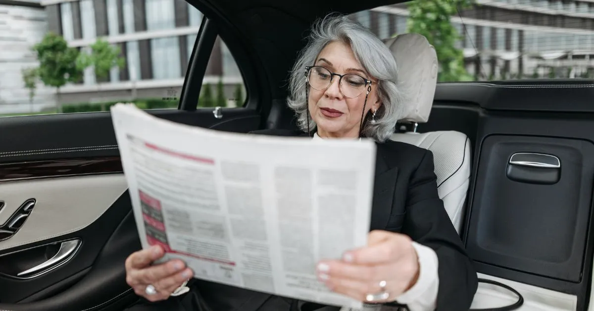 A Lady Reading Newspaper In A Driverless Autonomous Vehicle