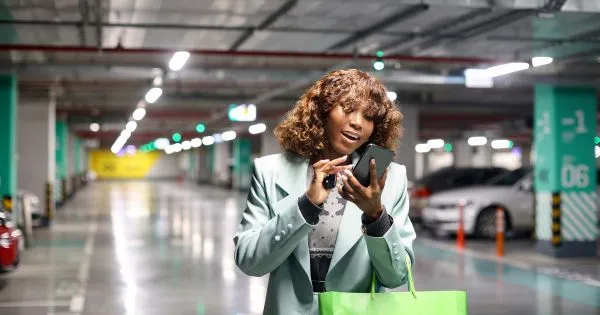A Lady Using Parking App On Her Phone In A Parking Lot A Lady Using Parking App On Her Phone In A Parking Lot