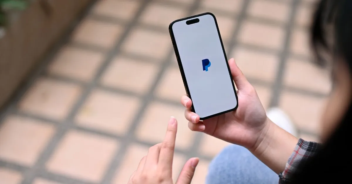 A Lady Using Paypal App On Her Phone
