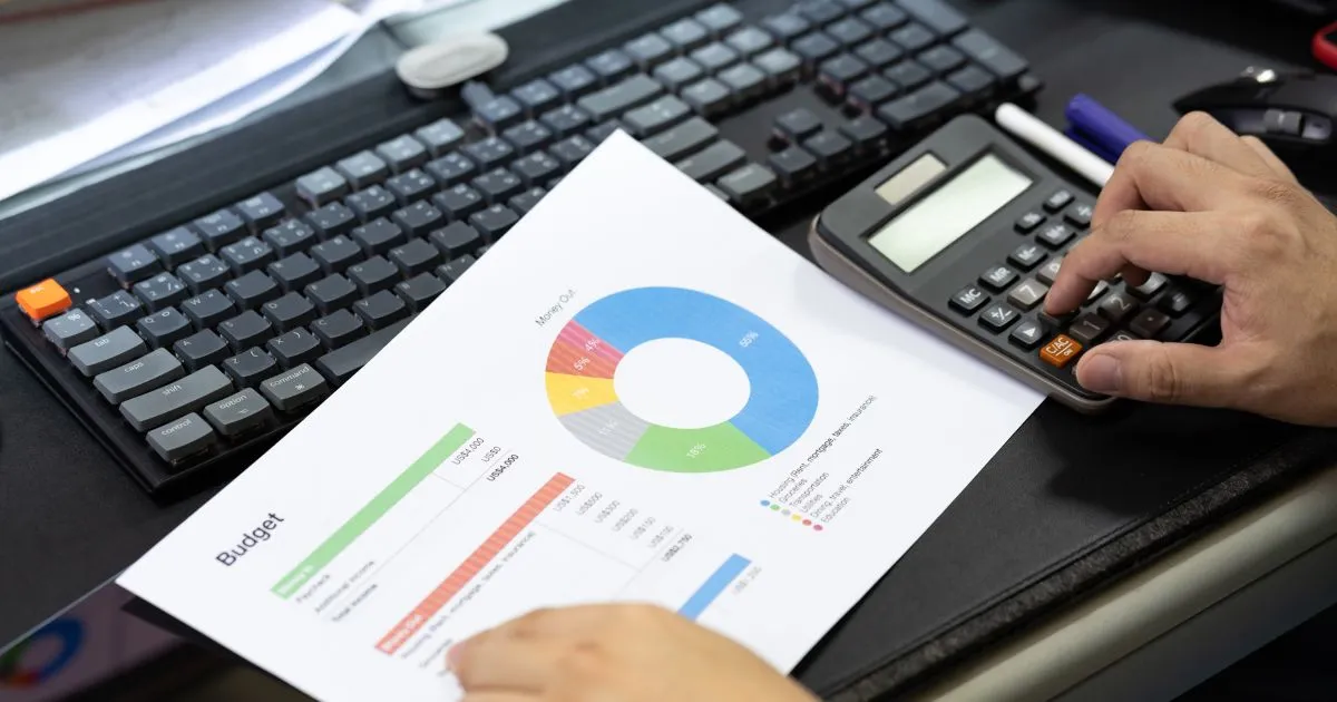 A Man Creating Budget By Using A Computer And A Calculator