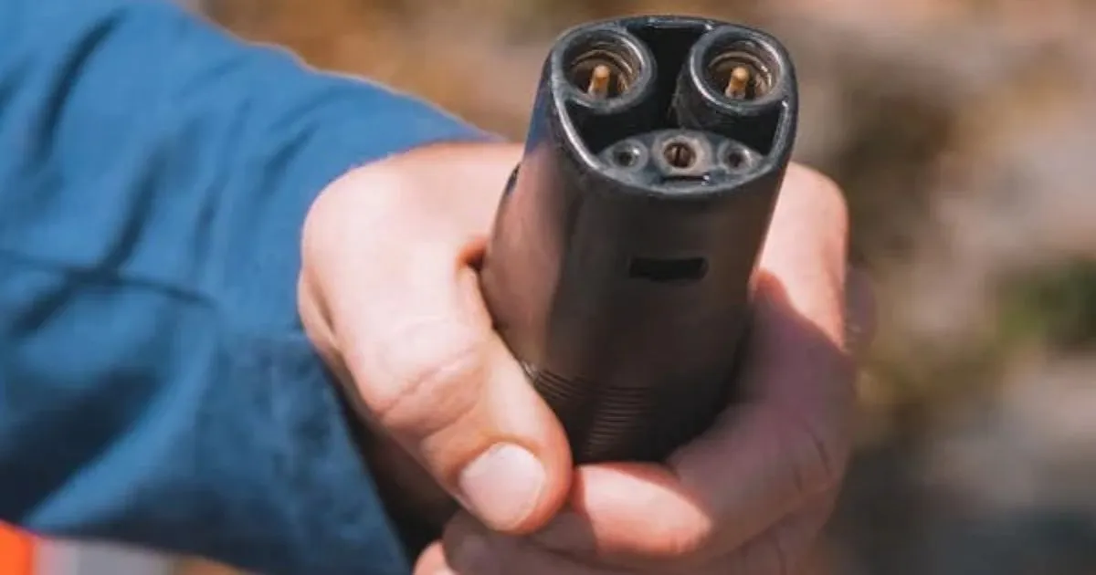 A Man Holding An Ev Charging Cable In His Hands