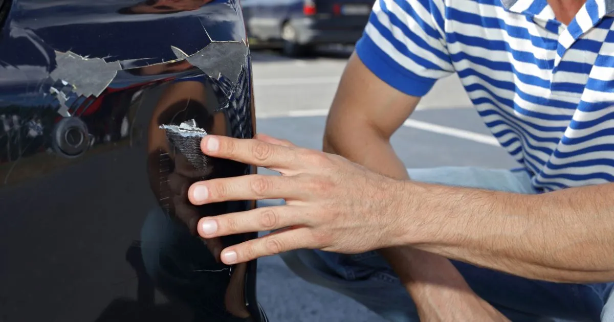A Man Looking At Scratches On His Vehicle Parked In A Car Park