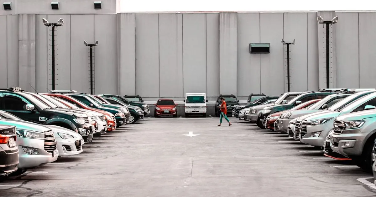 A Man Moving Toward His Car Parked In An Open Parking Lot Along With Many Other Vehicles A Man Moving Toward His Car Parked In An Open Parking Lot Along With Many Other Vehicles