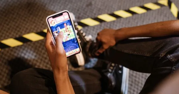 A Man Playing Puzzle Game On His Phone In A Car Park