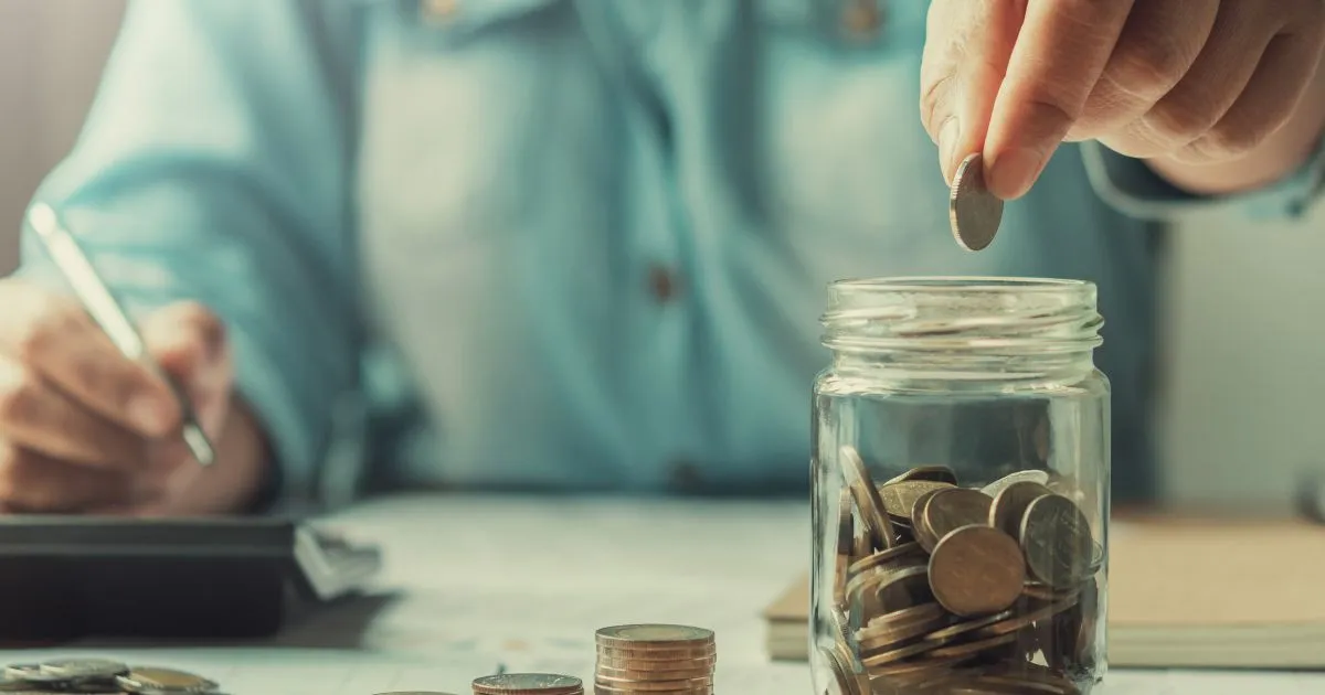 A Man Putting Coins In A Jar