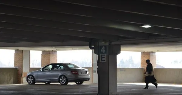 A Man Walking Towards His Car Parked In A Garage A Man Walking Towards His Car Parked In A Garage
