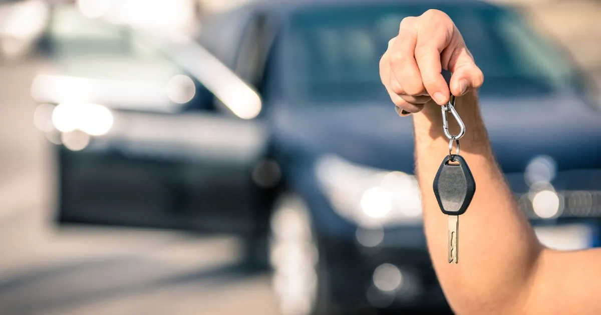 A Man With The Key Of A Second Hand Purchased Car Parked In A Parking Lot