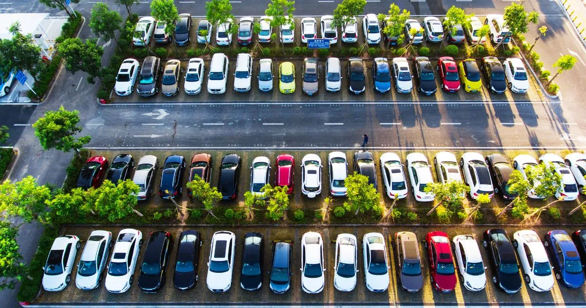 A Neat And Green Parking Lot With A Bunch Of Trees And Securely Parked Vehicles