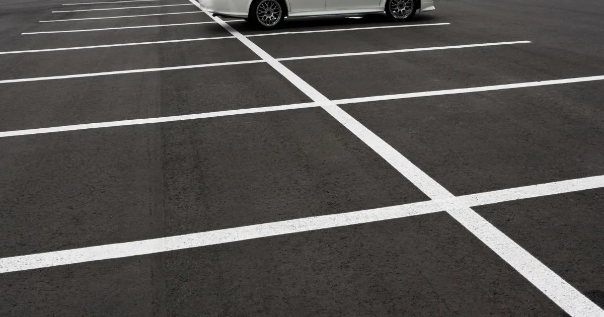 A Parking Lot With Numerous Empty Parking Spaces And A Parked Vehicle