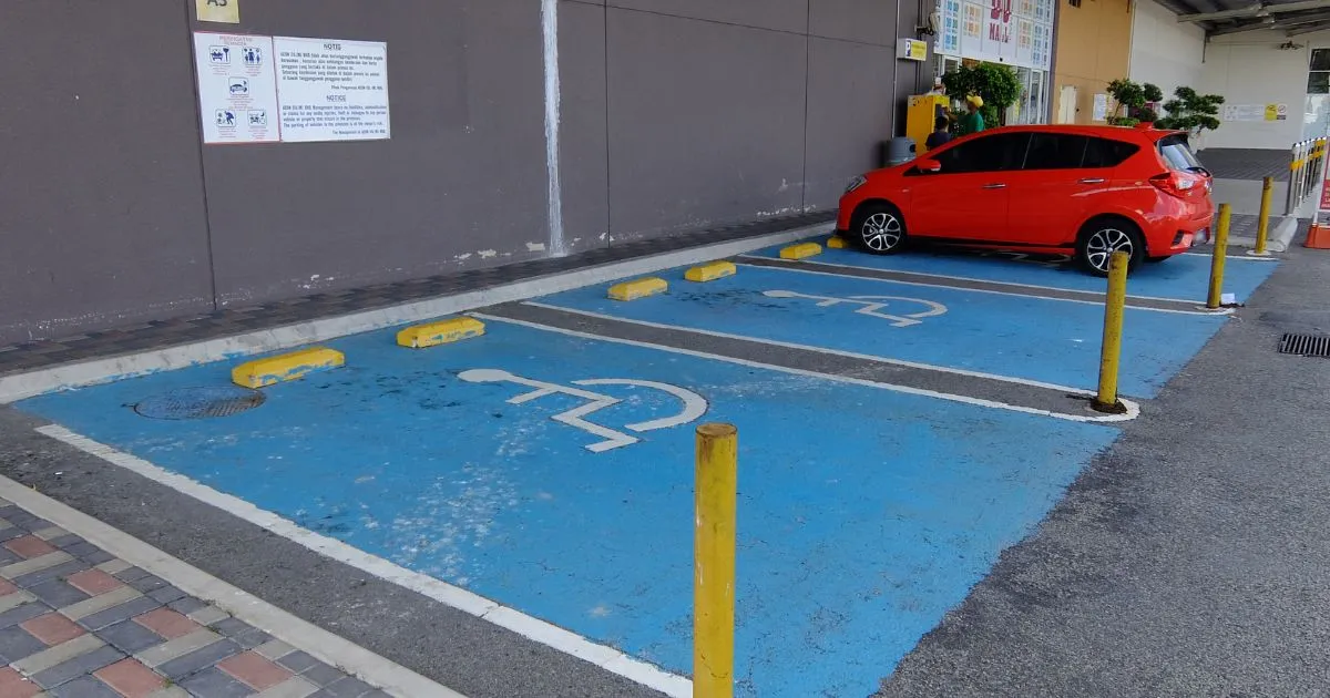 A Red Car Parked On An Accessible Parking Spot In A Car Park