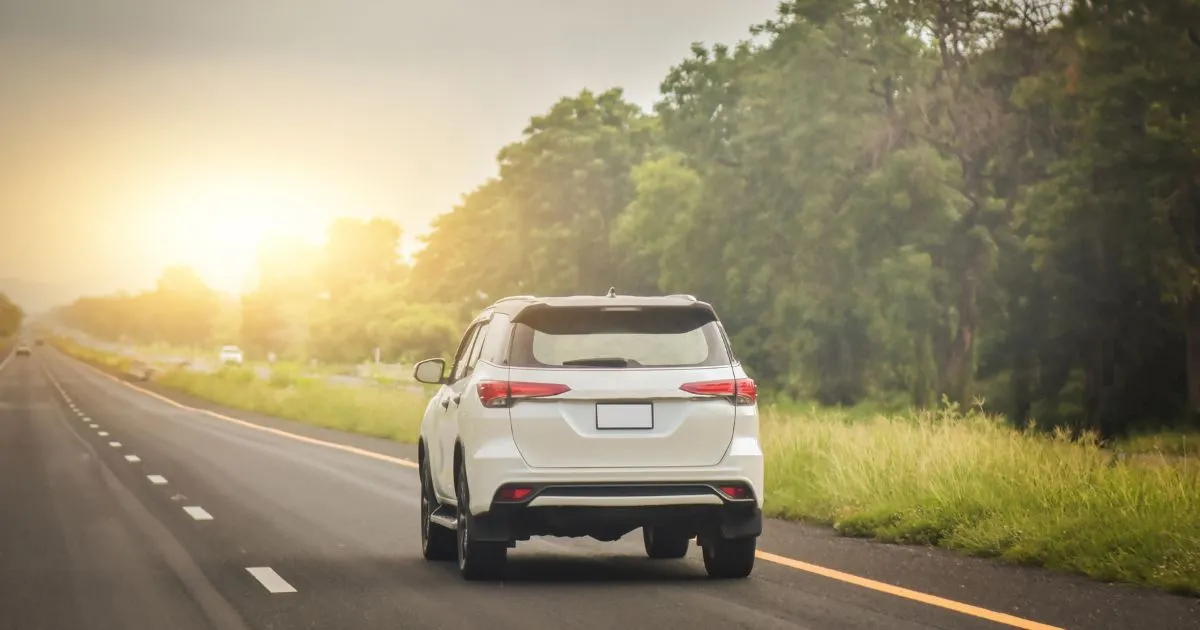 A Scenic View Of A Highway With A White Car Cruising Smoothly On It