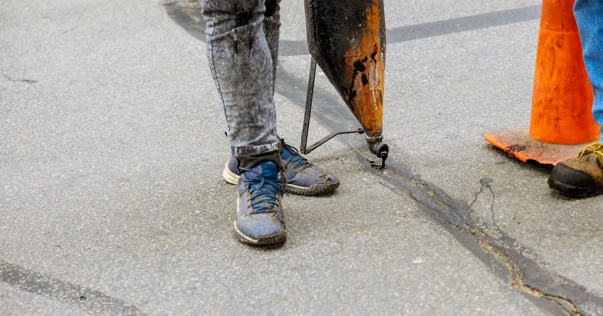 A Team Working On Filling Cracks In A Driveway