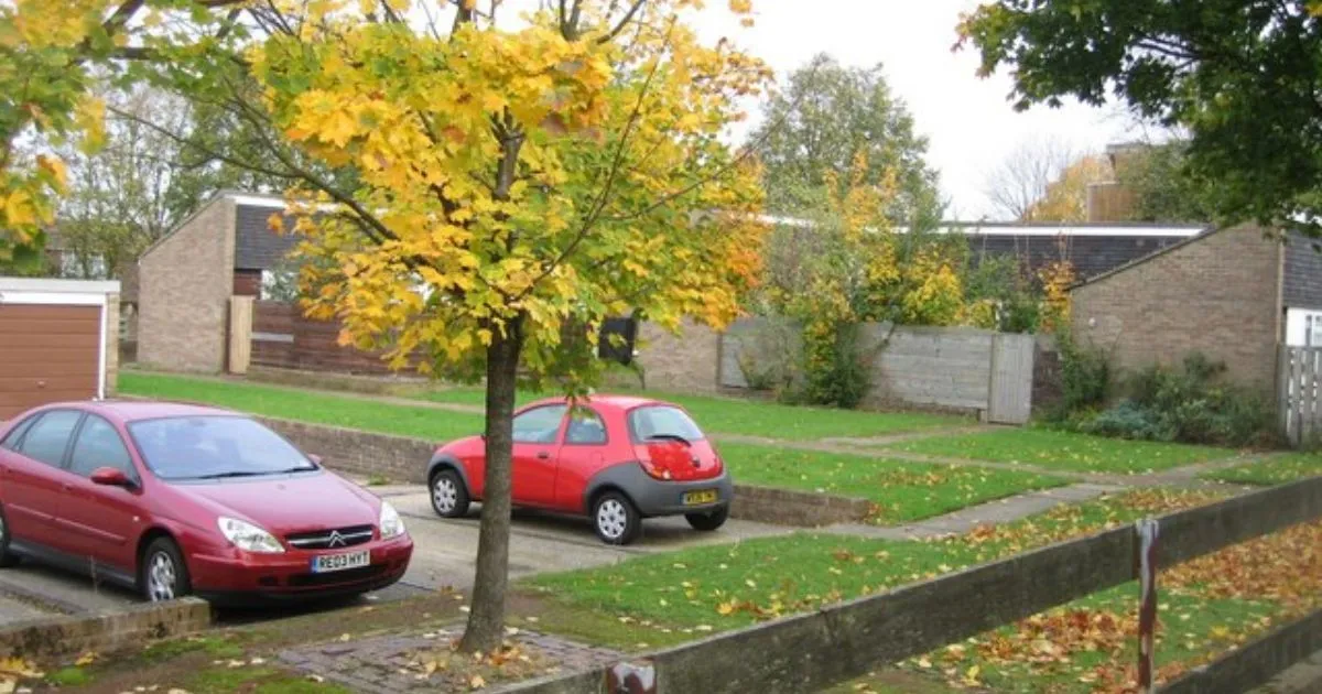 An Outdoor Residential Parking Lot With Two Vehicles Parked In It