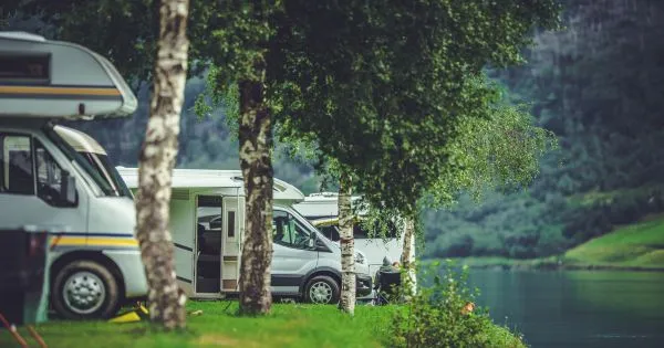 Multiple Rvs Parked On The Bank Of A Lake In The Woods Multiple Rvs Parked On The Bank Of A Lake In The Woods