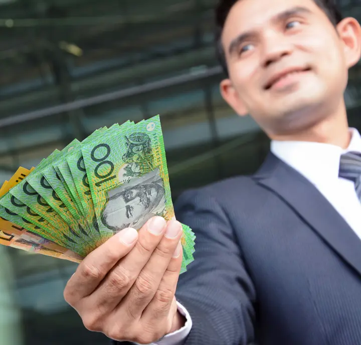 Businessman holding Australian one hundred dollar notes showing success when you earn money from parking space rentals.