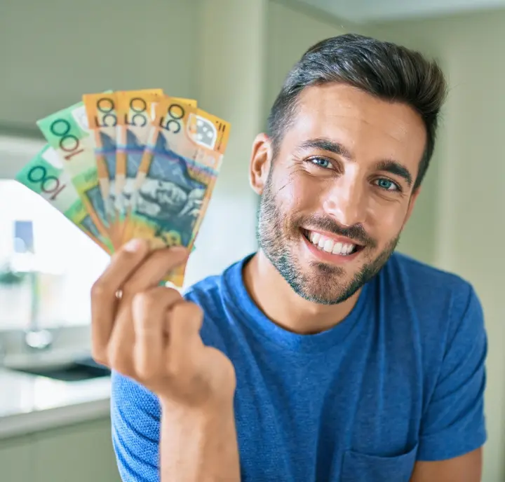 Man smiling while holding mixed Australian banknotes representing the income when you rent out your garage to drivers.